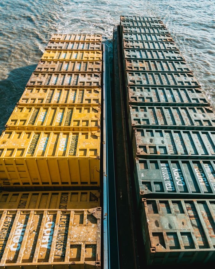 Drone view of colorful cargo containers on a ship navigating through the ocean waters.